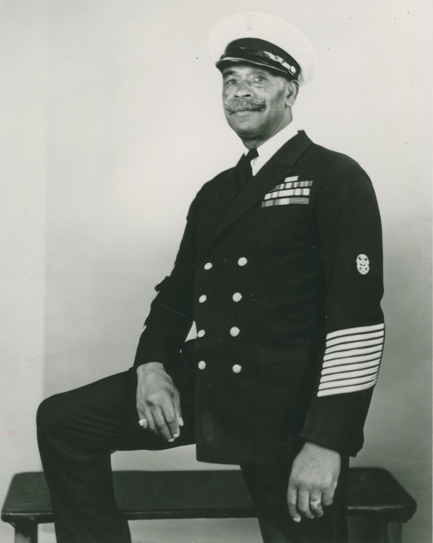 John Henry “Dick” Turpin, seated, in Navy dress uniform with rows of service stripes on his sleeve