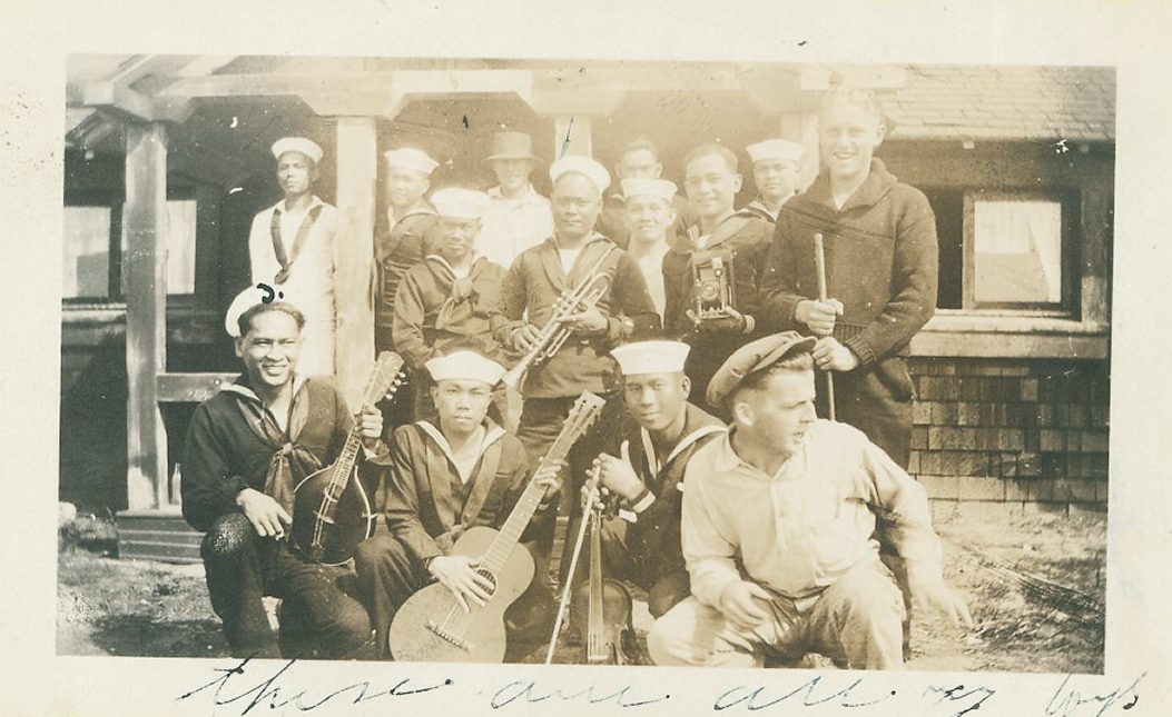 Filipino Navy musicians in white uniforms pose with guitars, a violin and other instruments