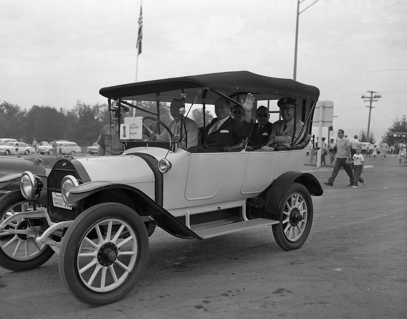 A man waves from an open antique touring car at the Hood Canal Bridge opening ceremony
