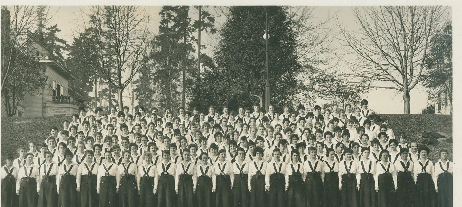 Rows of women in matching Navy uniforms assembled on a hillside